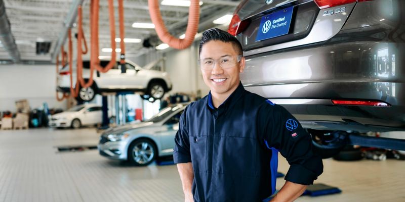 Certified VW technician in front of VW vehicle.