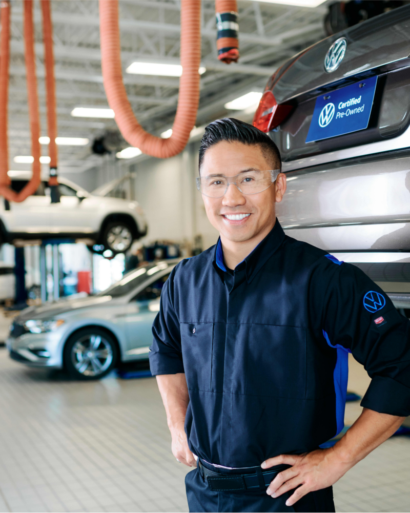 Certified VW technician in front of VW vehicle.