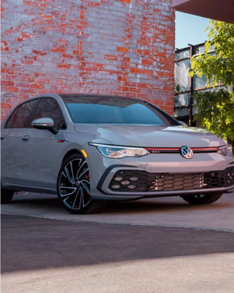 Volkswagen GTI in front of red brick wall.