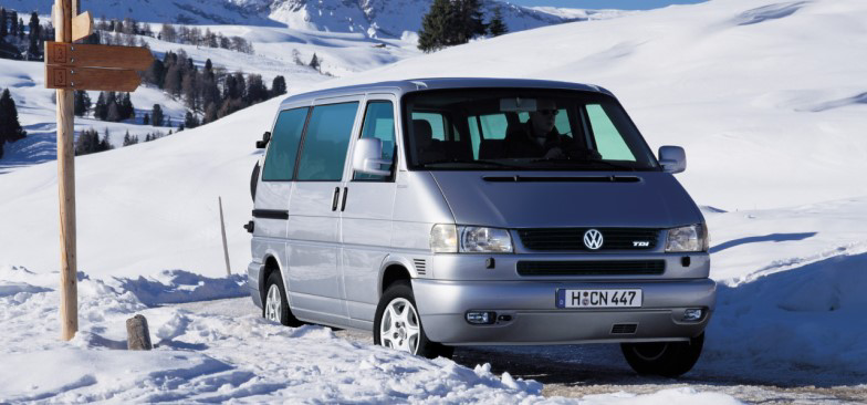 Starsza generacja Volkswagena California jedzie po ośnieżonej drodze.