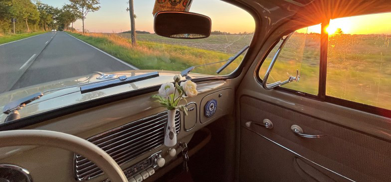Kwiaty w wazonie na desce rozdzielczej w starszej generacji Volkswagena California.