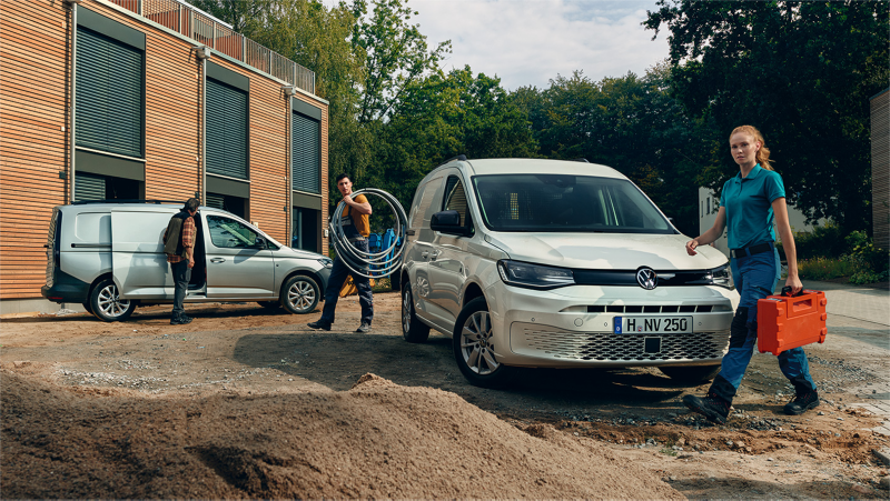 Primer plano de un VW Caddy Cargo junto a dos autónomos profesionales cargando material.