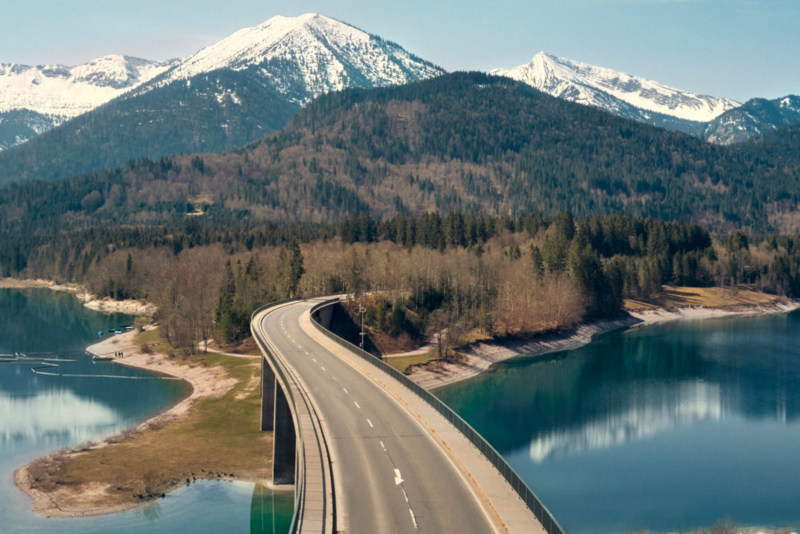 Vue d'une route surplombant l'eau et se dirigeant vers les montagnes.