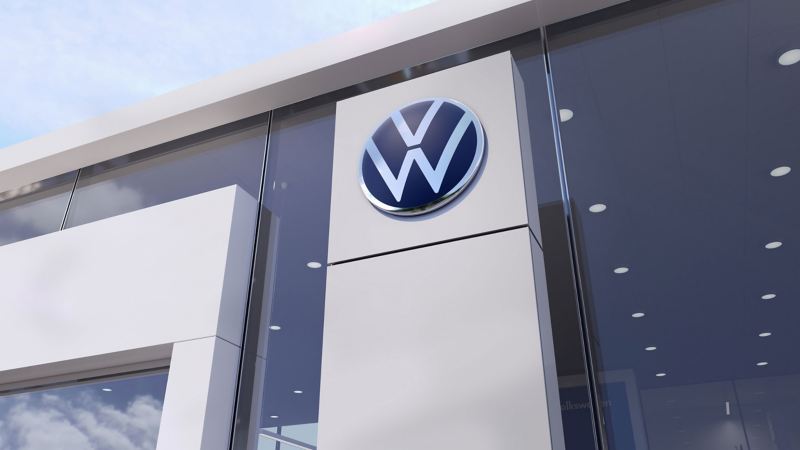 A large VW logo on the front window of a VW dealership