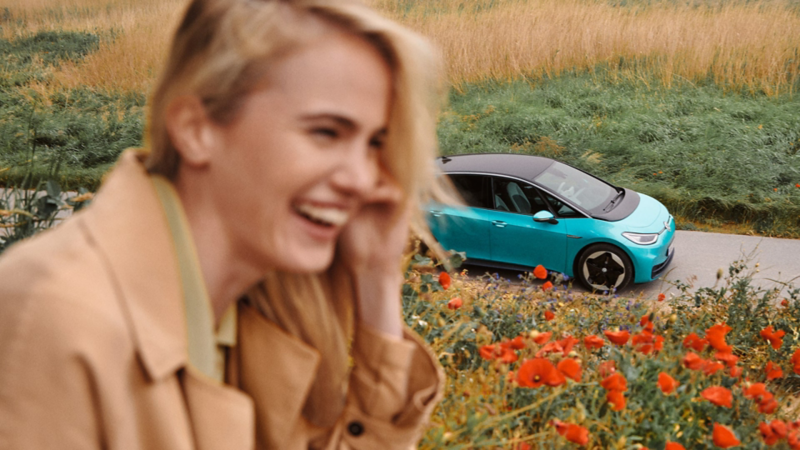 I forgrunden ser man en smilende kvinde, og i baggrunden en VW ID.3.