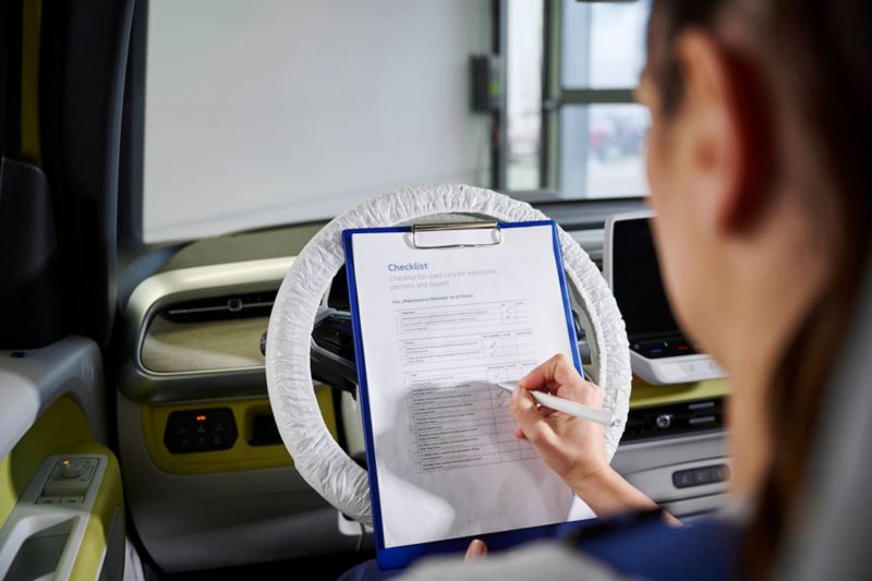 Une technicienne Volkswagen fait le point sur une check-list à l'intérieur d'un véhicule