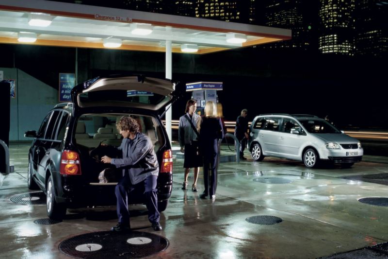 Des Volkswagen Tourans font le plein dans une station service la nuit.