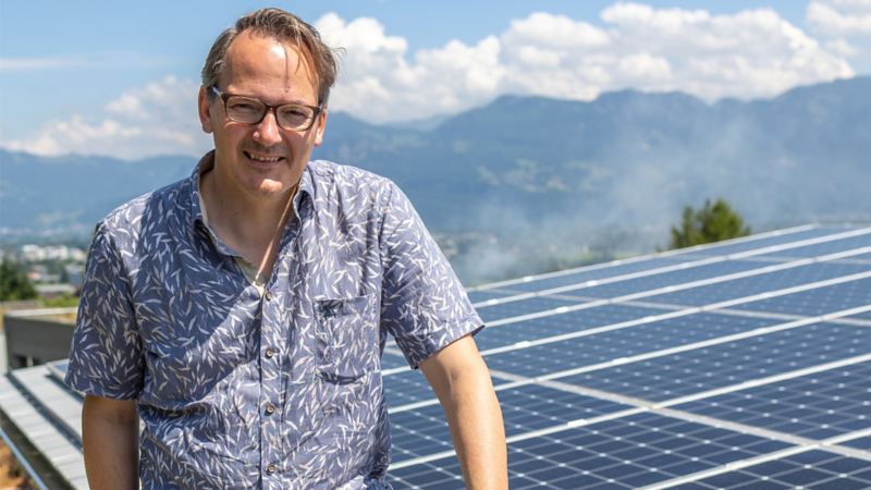 Christof Schmid in piedi sul tetto di fronte alla propria fonte di energia solare.