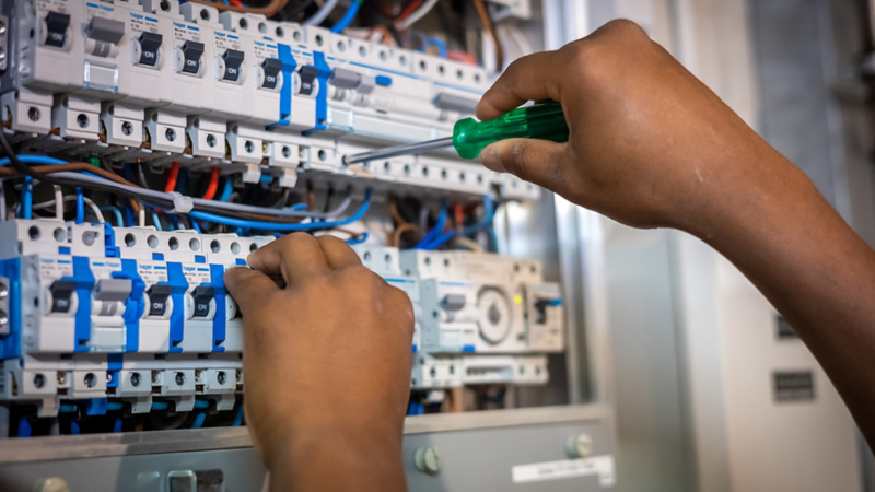 Ein Man passt etwas an der elektrischen Schalttafel an