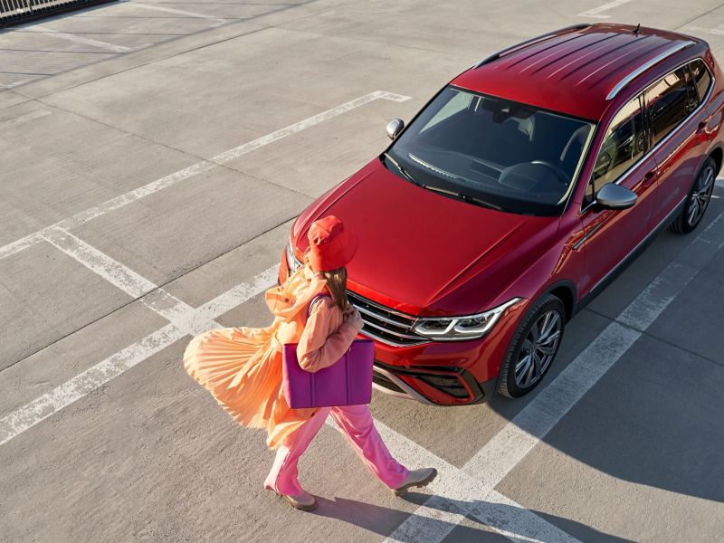 Woman walking in front of red VW car