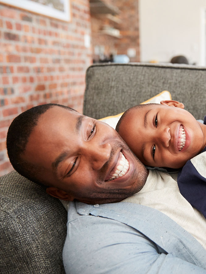 father and son happily relaxing on the couch