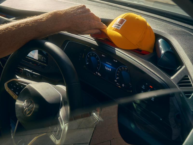 Courier boy placing cap onto dash of Volkswagen Caddy Cargo.