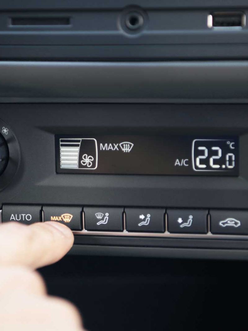 Clima de auto Volkswagen. Vento Join 2022. Mano aprieta botón para regular temperatura. 