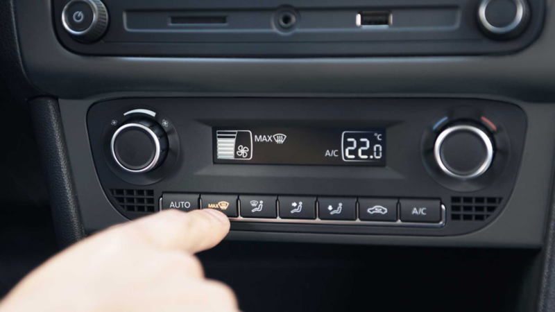 Clima de auto Volkswagen. Vento Join 2022. Mano aprieta botón para regular temperatura. 