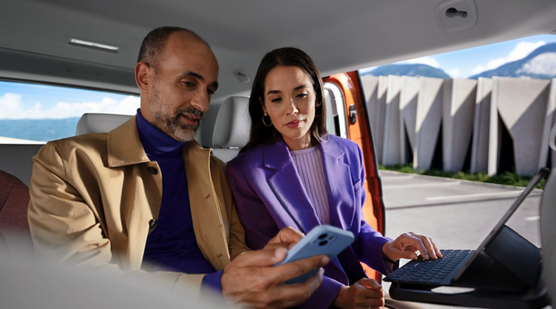 Una mujer y un hombre mirando el móvil, sentados en el VW ID. Buzz.