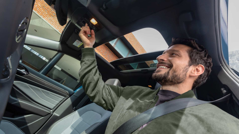 Hombre abre el techo panorámico desde el asiento del conductor.Modificado con inteligencia artificial