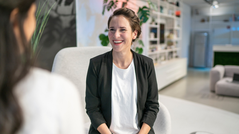 Interviewer de dos et Franziska Killiches assise sur une chaise et riant.
