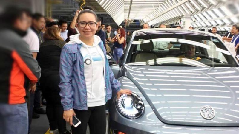 Isabel Jaramillo parada al costado de un Volkswagen Beetle color gris 