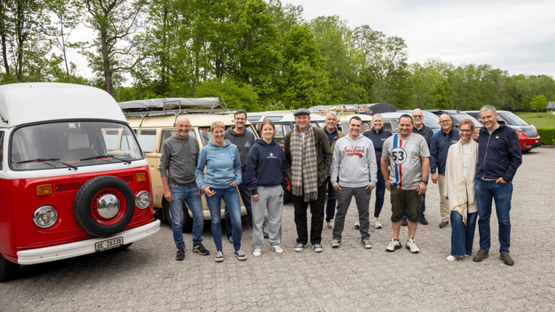 Photo de groupe des participants avec des VW Bus en arrière-plan.
