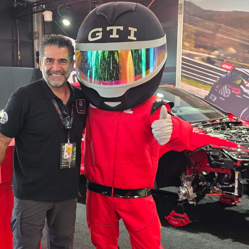 Presidente del club GTI posa junto a botarga con casco negro de Volkswagen.