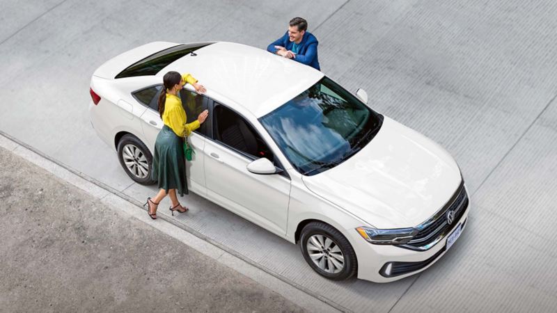 Volkswagen Jetta 2024 en color blanco, con pareja recargada sobre las ventanas y parte del techo.