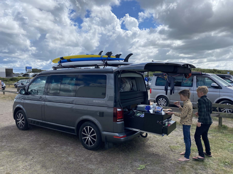 Två barn står vid bagageluckan på en VW California