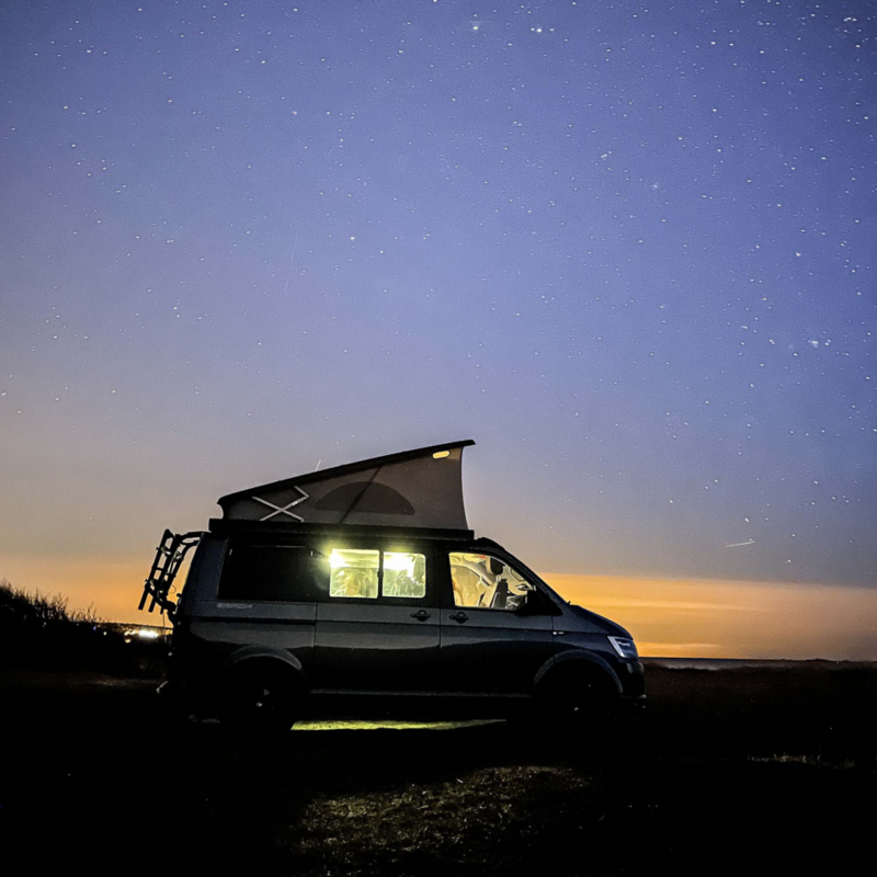 En VW California med popup-tak i skymning