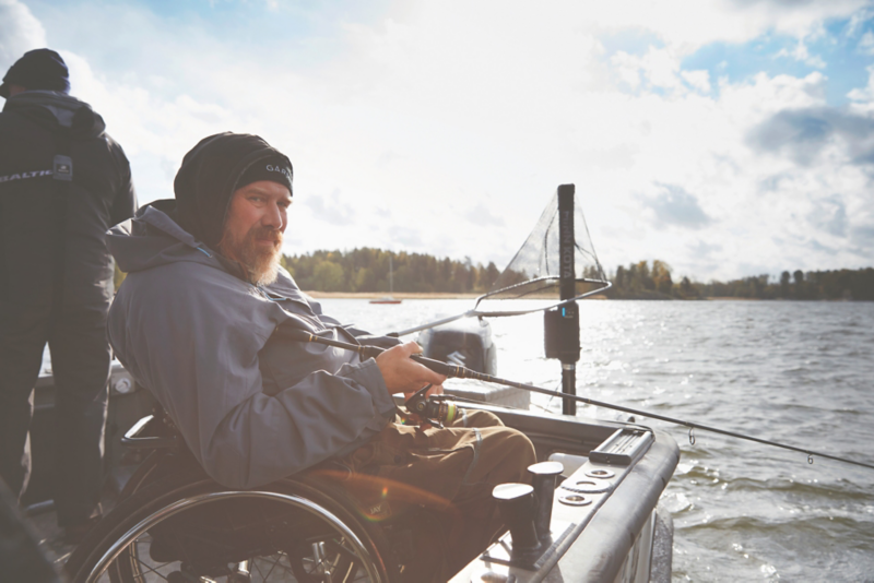 En person sitter i en båt ute på sjön i naturnära omgivning