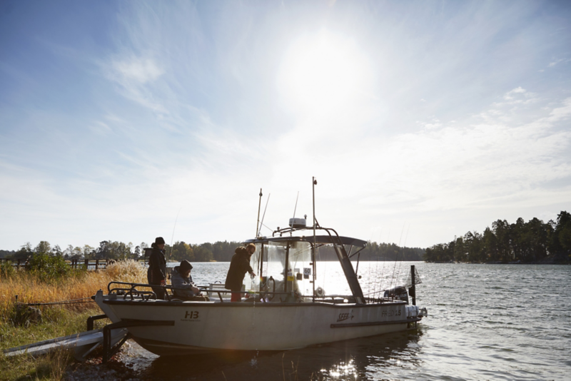 Tre personer på en båt ute på sjön en solig dag