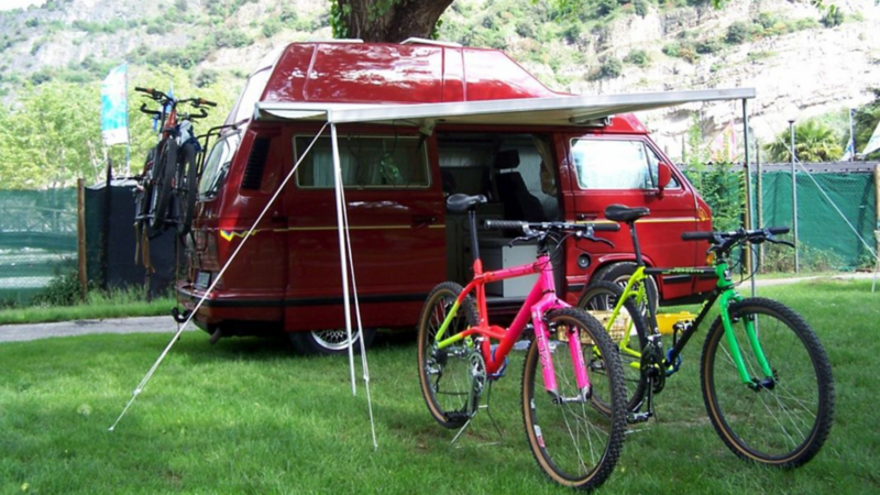 Jürgens roter zum Camping aufgebauter VW T3 California, zwei Mountainbikes stehen unter dem. Vordach.