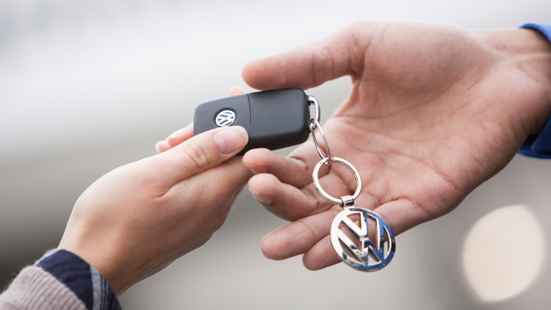 Une clé de voiture VW est transmise de main en main.