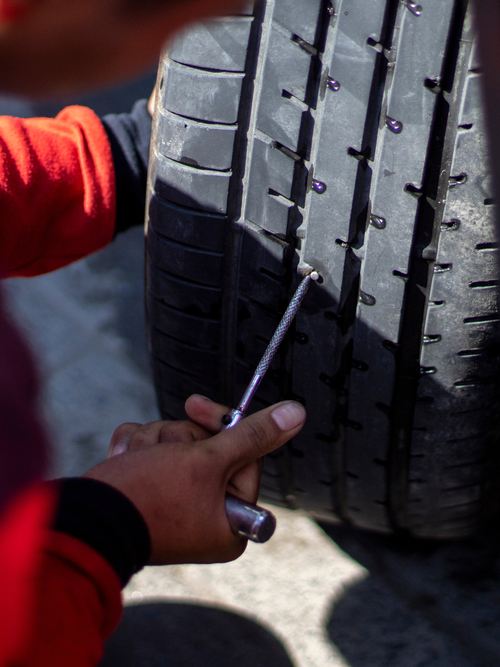 Mecánico arreglando una rueda con un kit antipinchazos