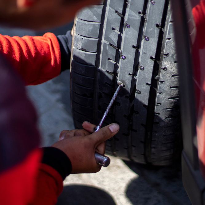 Mecánico arreglando una rueda con un kit antipinchazos