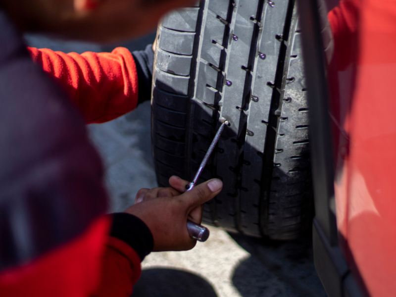 Mecánico arreglando una rueda con un kit antipinchazos