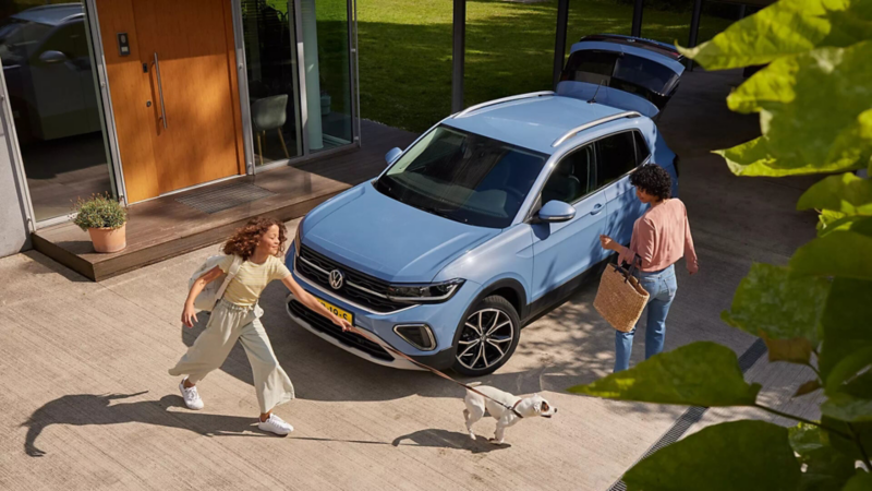 Blauw T-cross met kind en vrouw op de oprit 