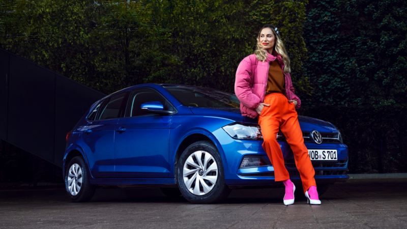 Chica sentada la parte frontal de un Volkswagen Polo azul