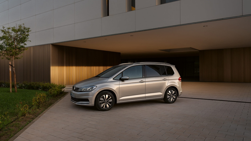 Vista lateral de un Volkswagen Touran aparcado frente a una casa