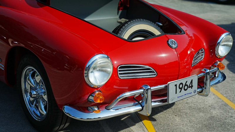 Cofre abierto de auto clásico Volkswagen rojo modelo 1964 muestra llanta de refacción.
