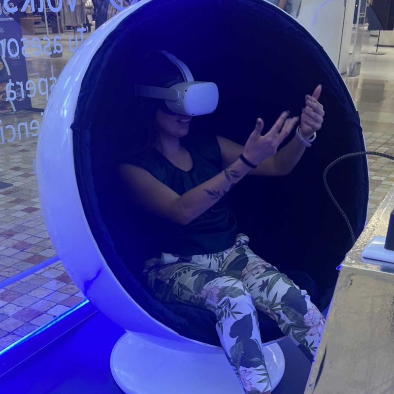 Mujer con lentes de realidad aumentada en cabina de Metaverso Volkswagen. 