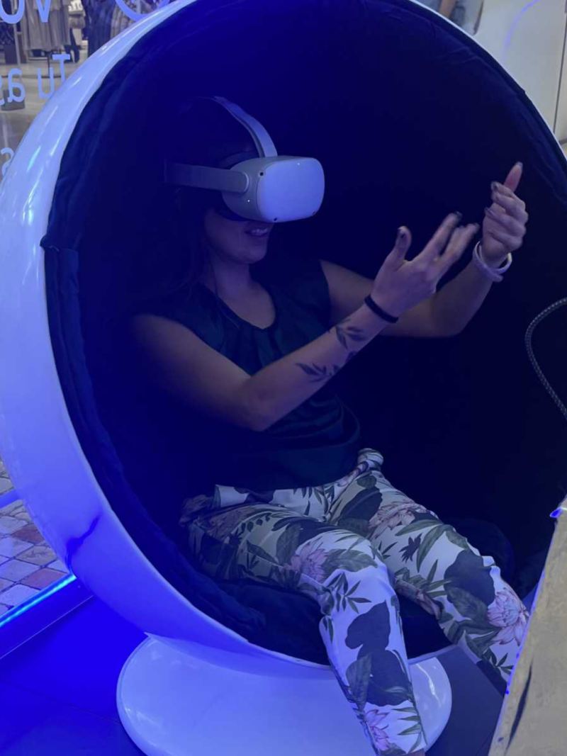 Mujer con lentes de realidad aumentada en cabina de Metaverso Volkswagen. 