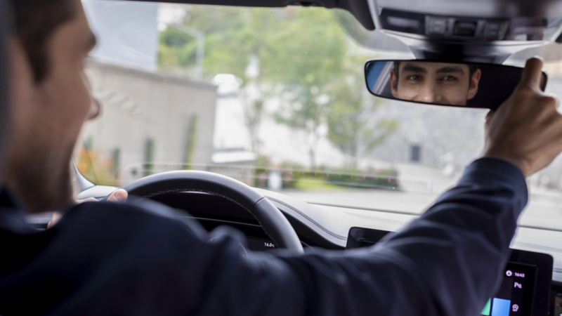 Conductor revisa su espejo retrovisor mientras maneja su auto VW.