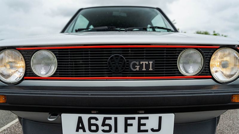 A front on shot of a silver Mk 1 Golf GTI showing the red stripe around radiator grille