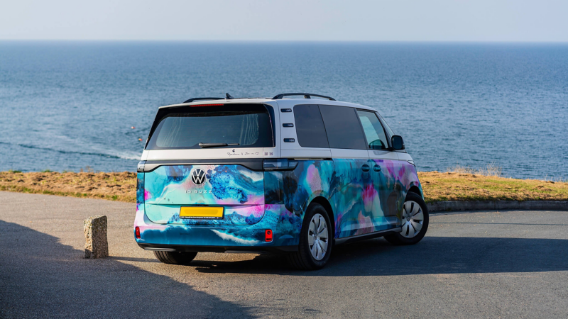 Rear three-quarter view of artwork-wrapped ID.Buzz parked by the sea