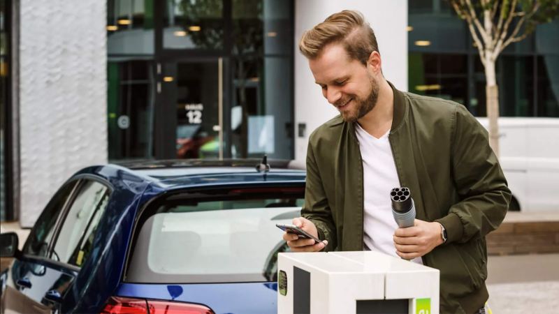 Person pictured with a VW charger plug in their hand