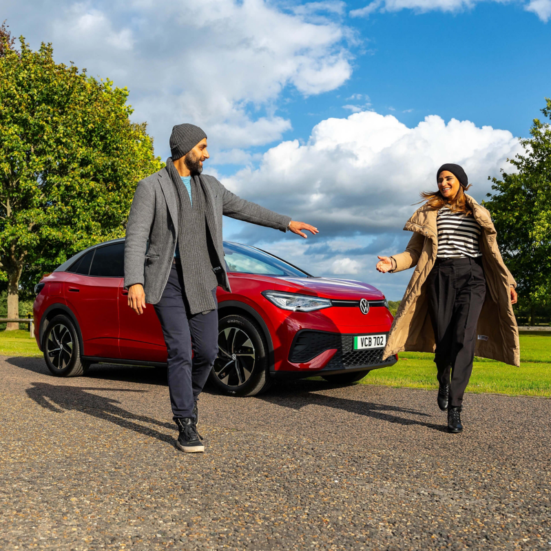 A couple walking together in front of an ID. range vehicle