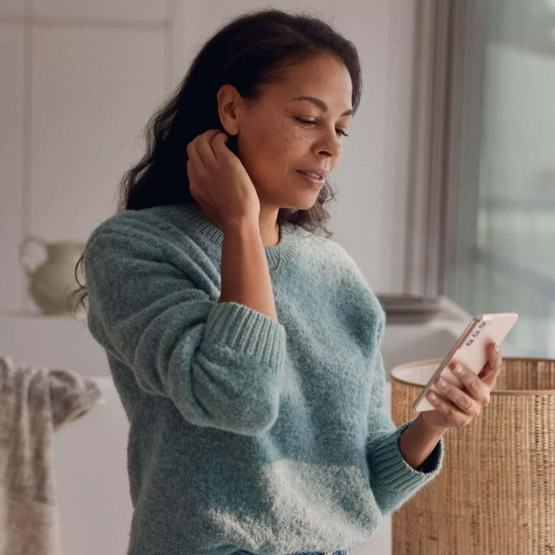 Person wearing a fluffy jumper and holding a mobile phone in their hand