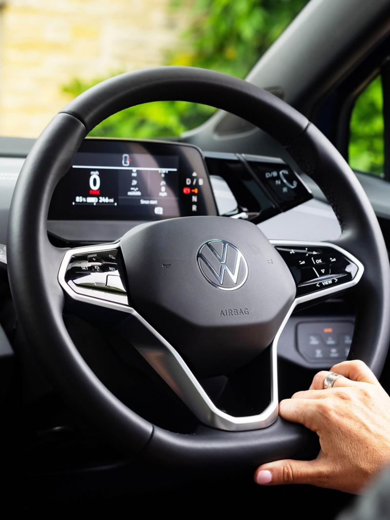 a close up of a hand on a VW steering wheel
