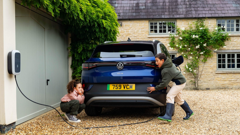 two children next to a parked ID.4 plugged into a wallbox charging