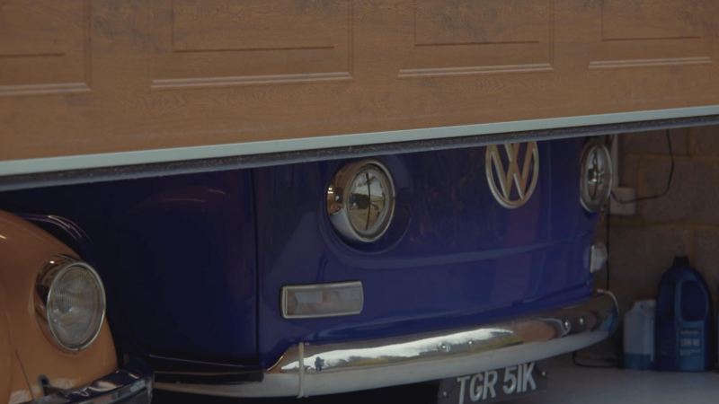 A photo showing a Volkswagen Beetle and Volkswagen camper parked in a garage. 
