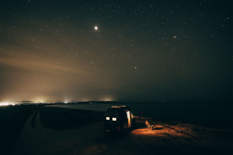 Magazine California VW, tout sur les itinéraires et voyages, Grand California garé dans la nuit avec un voyageur